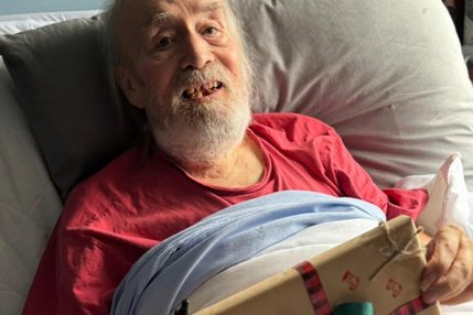Elderly man in bed receiving present