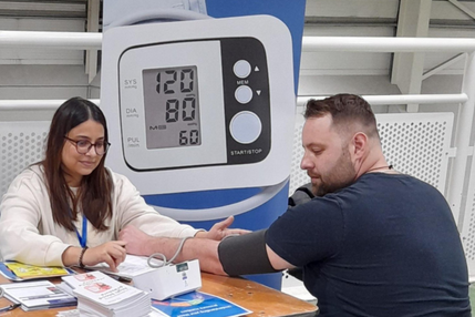 Volunteer Health Navigator giving attendee a blood pressure test