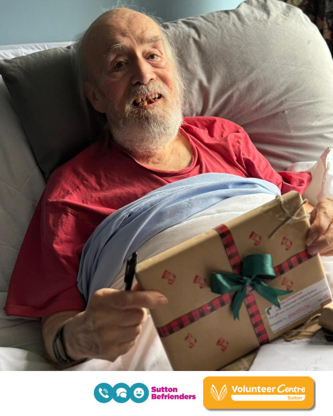 Elderly man in a bed receiving a Christmas Present